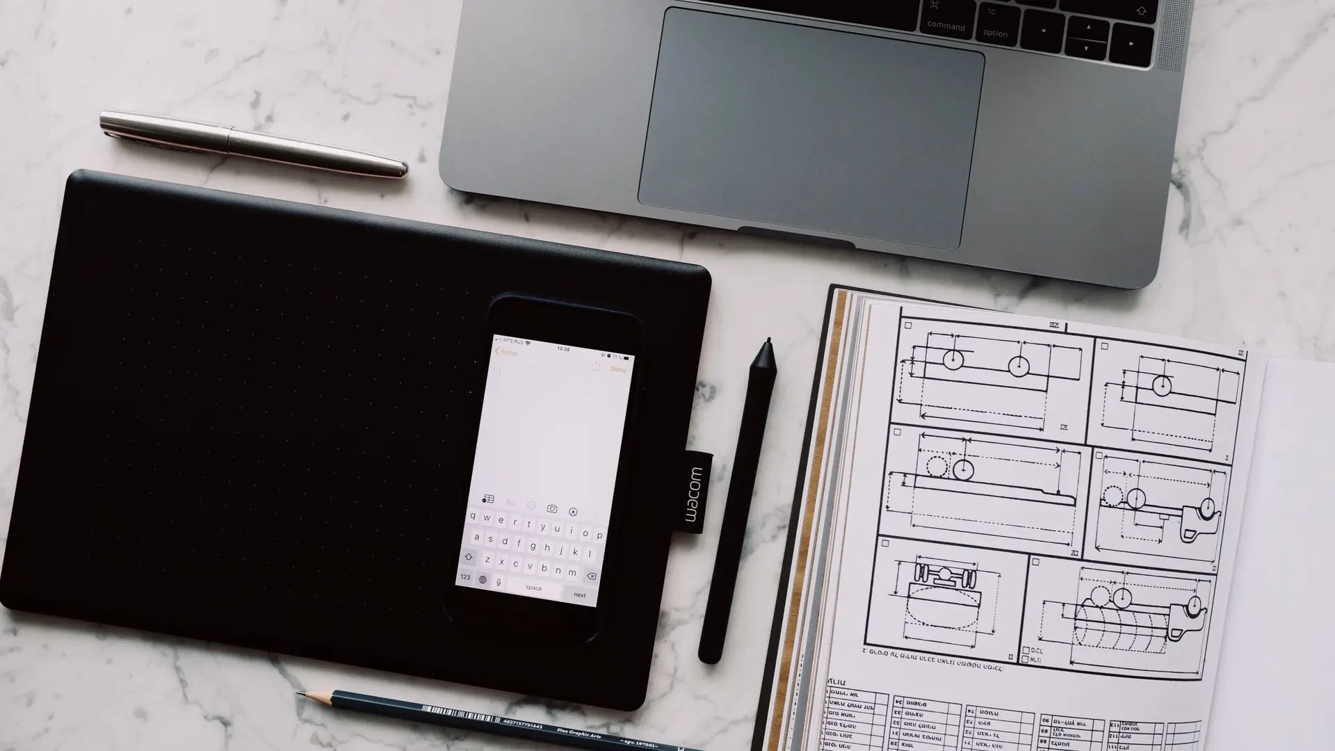 Open laptop, phone and project drawings on a desk